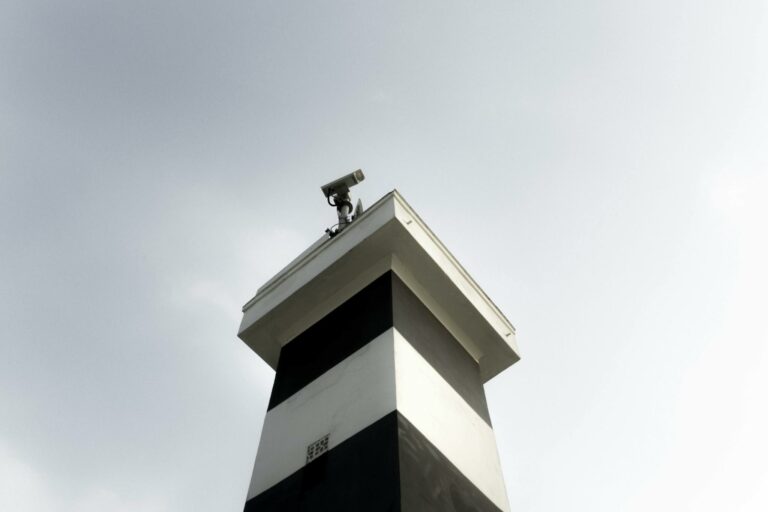 A modern surveillance tower equipped with a CCTV camera against a clear sky, showcasing security and technology.